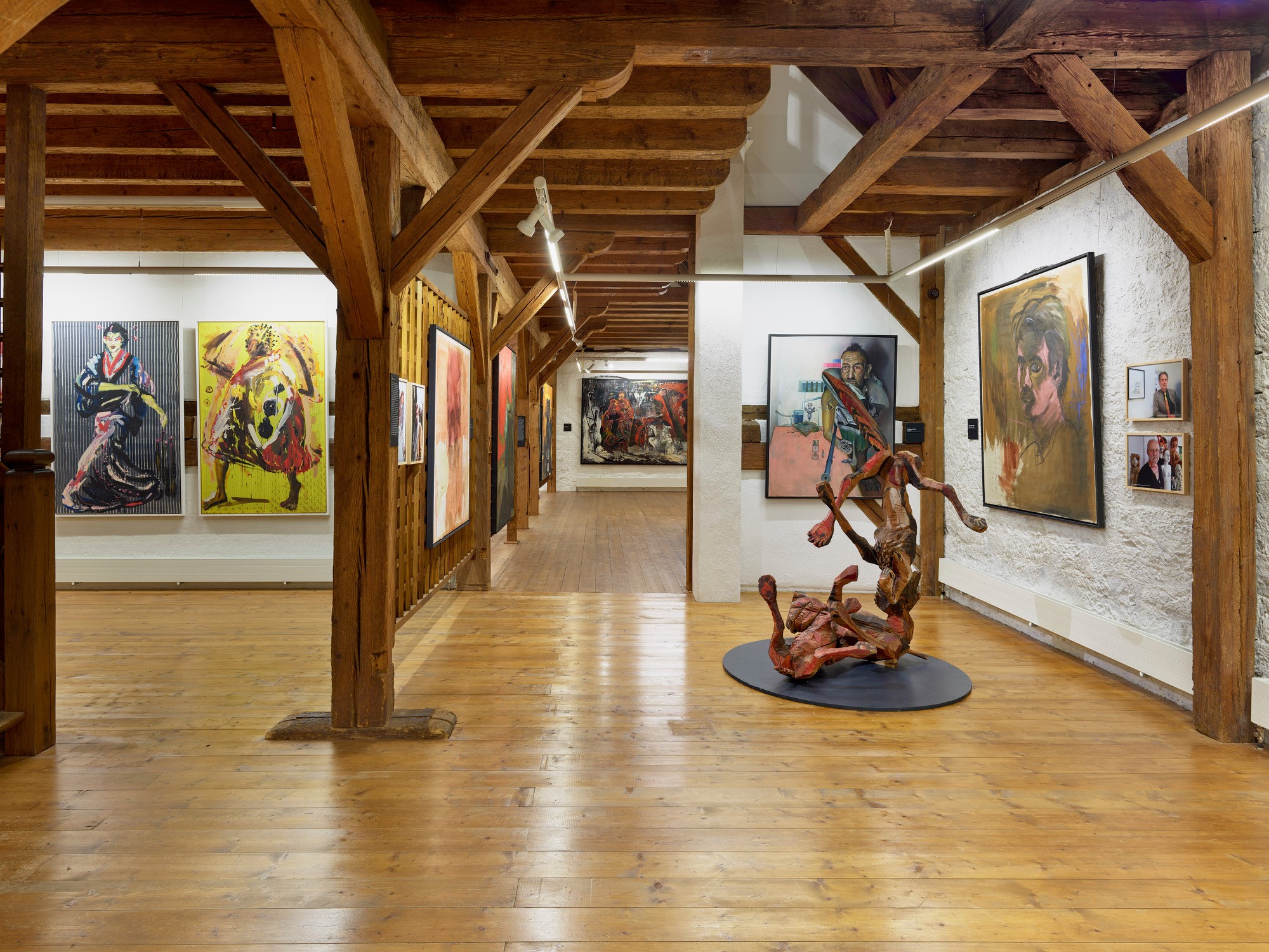 Blick in ein Museum mit großflächigen, farbenfrohen Malereien und einer Holzskulptur